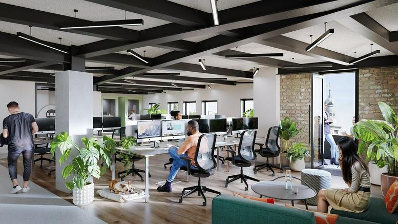 Bright open-plan office with exposed black ceiling beams, wooden floors, and potted plants.