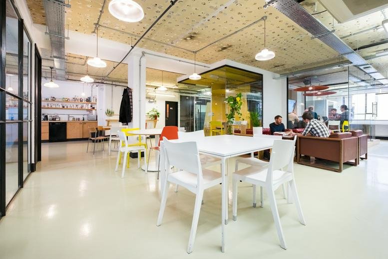 Wide-angle view of a bright coworking space at 6-8 Bonhill Street with white tables and wooden ceilings.