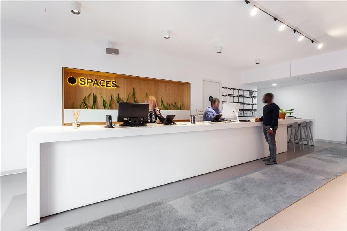 Modern white reception desk with professional staff, warm wood accents and brand signage.