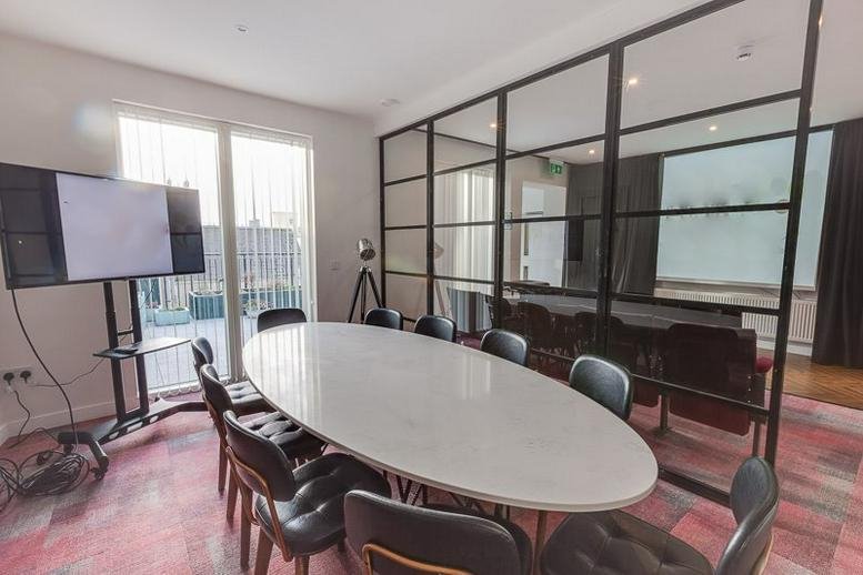 Conference room with a white table and black chairs set against a glass wall.