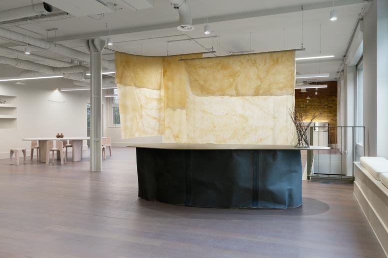 Spacious reception area at 60 Ironmonger Row with a black curved desk and large hanging parchment art.