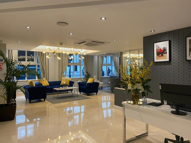Spacious reception area with blue sofas and marble flooring.