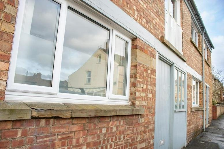 Exterior brick facade of Unit 2, 60 Queens Street, Stamford, Lincolnshire with large white-framed windows.