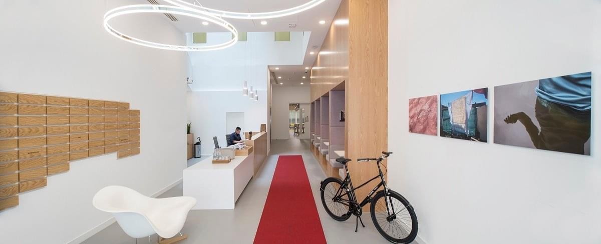 Spacious reception area at 60 St Martins Lane with a red carpet, bicycle, and modern seating.