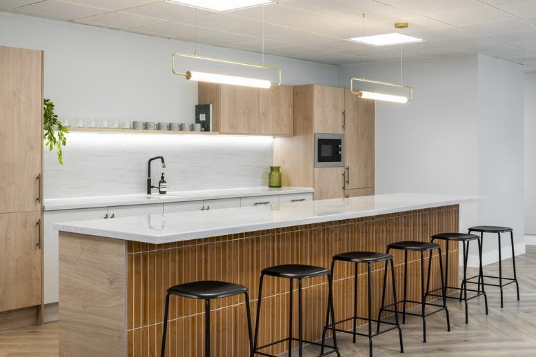 Modern kitchen with light wood cabinetry, white marble countertops, and an integrated microwave.