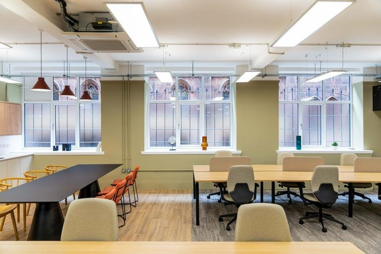 Open-plan office area with natural light, timber floors, and rows of desks.