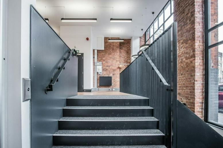Modern staircase with dark grey railings and industrial brick wall accents.