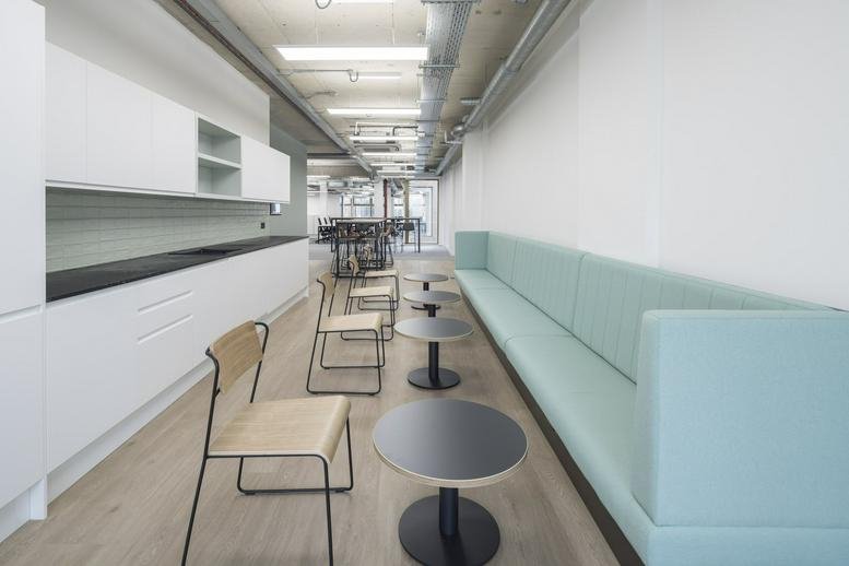 Spacious communal breakout area at 66 Pentonville Road with a long teal bench and white cabinetry.