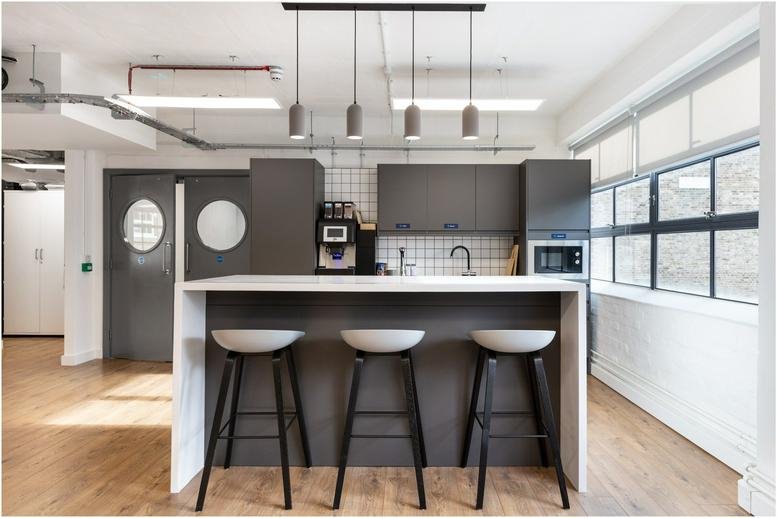 Modern communal kitchen at 67-69 Cowcross Street featuring a grey island with bar stools and pendant lighting.