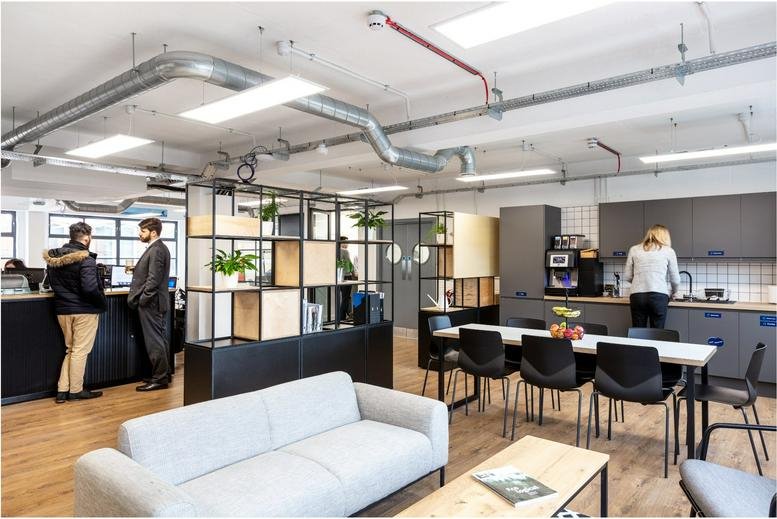 Spacious open-plan lounge and break area with soft seating and industrial-style exposed ducting.
