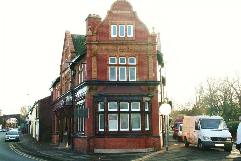 Exterior view of the ornate red brick corner building featuring large bay windows.