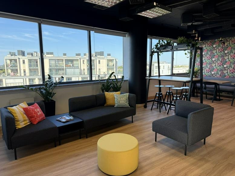 Bright coworking lounge at 69, Aleja Niepodległości, Warsaw with modular sofas and city views.