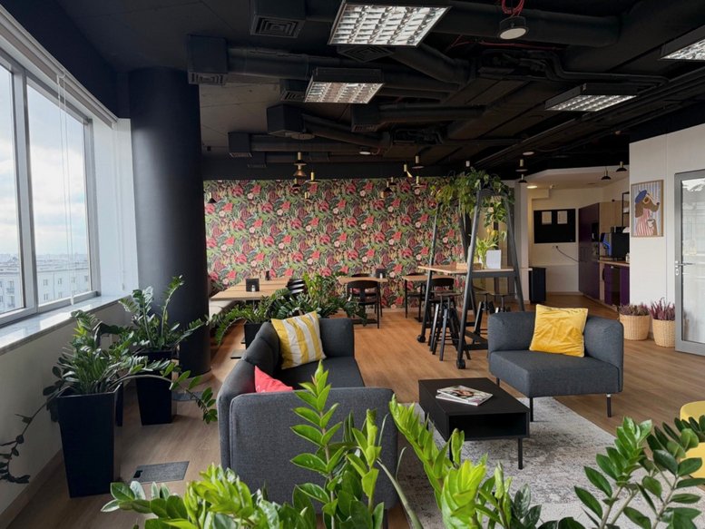 Stylish lounge area at 69, Aleja Niepodległości, Warsaw with grey sofas, plants, and floral wallpaper.