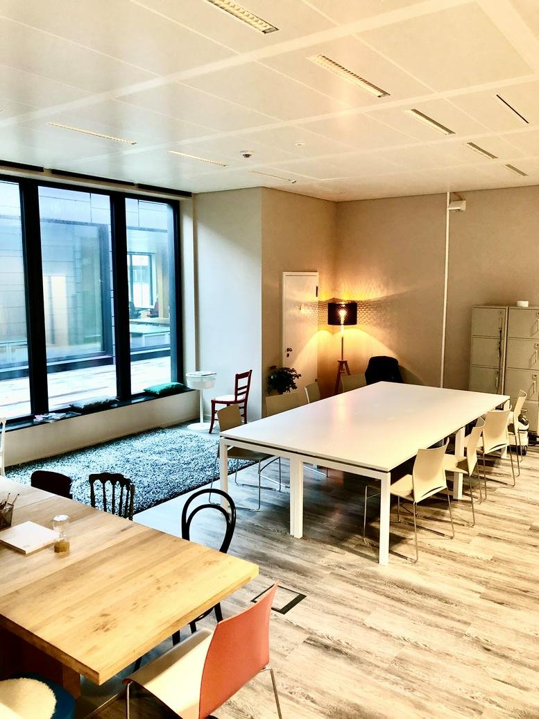 Spacious coworking area with wooden tables, colorful chairs, and large windows at 7 avenue du Swing, Belvaux.
