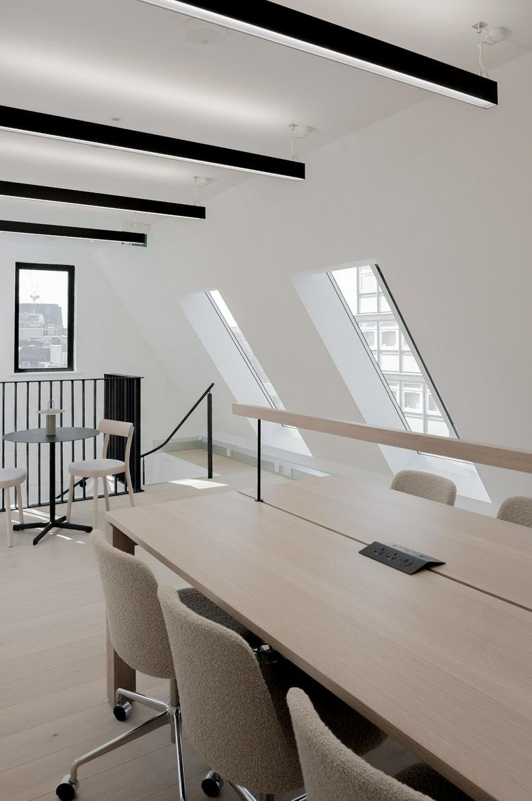 Wide-angle view of spacious open-plan office with sloped windows and natural light.