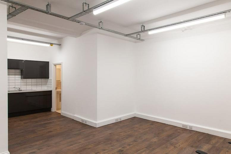 Spacious open-plan studio at 7 Heather Close, Lambeth featuring wooden floors and industrial lighting.