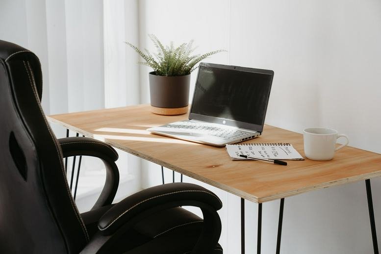 Bright desk setup with a laptop and coffee mug in a sunny office space.