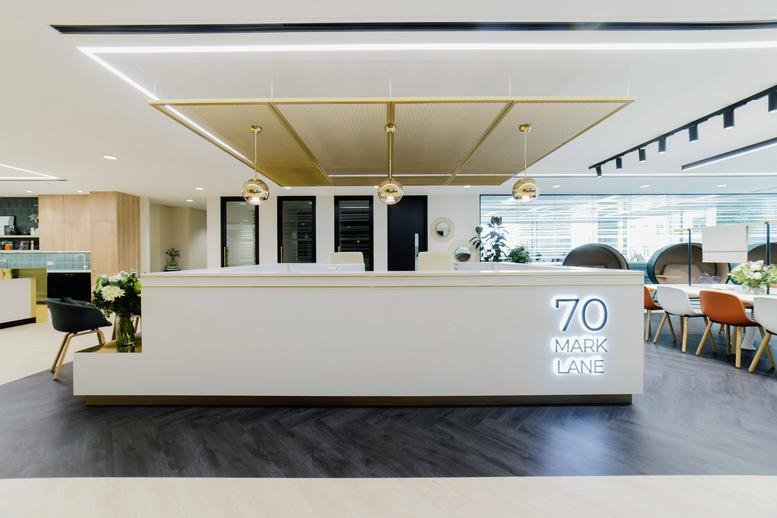 Modern white reception desk at 70 Mark Lane, London, EC3R with gold pendant lights and Herringbone floors.