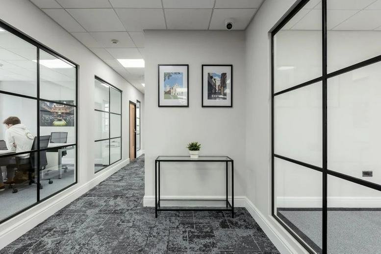 Modern office corridor at 72 Paris Street with glass partition walls and framed artwork.
