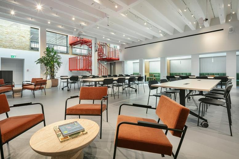 Spacious communal lounge at 76 Portland Place with velvet chairs and a red feature staircase.