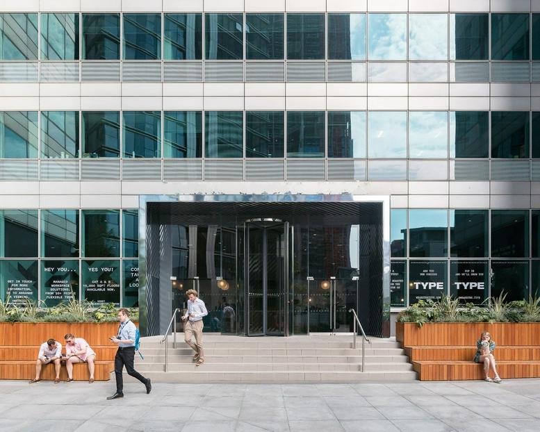 Exterior entrance of Sierra Quebec Bravo featuring a revolving glass door and wooden bench seating.