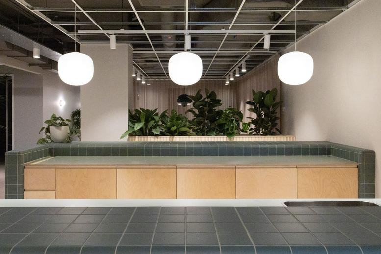 Spacious communal lounge at 77 Marsh Wall Road with teal tiled benches and wooden cabinets.