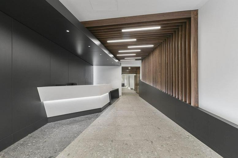 Modern lobby at 79 Chichester Street, Centre House featuring a white reception desk and wood-slat ceiling accents.