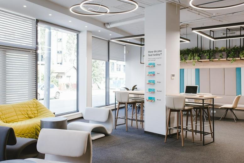 Spacious sunlit common area at Twins Centre with modern white seating, high tables, and ring pendant lights.