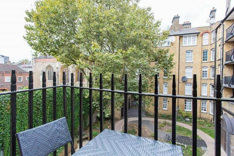 Balcony view from 8 Albemarle Way overlooking a shared courtyard with mature trees and brick architecture.