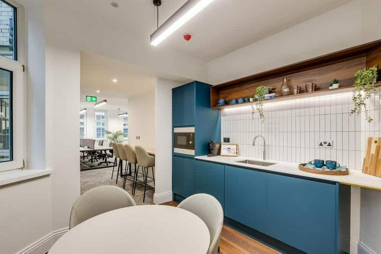 Modern kitchenette featuring deep blue cabinetry and a white tiled backsplash.