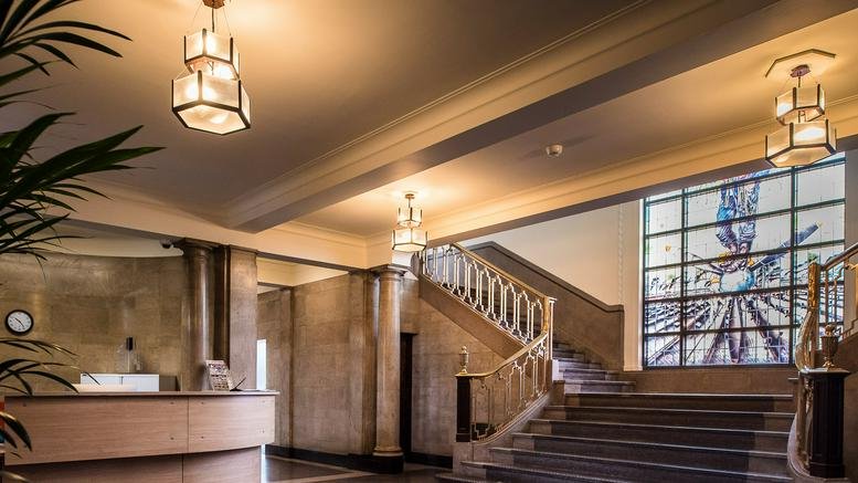 Grand art deco lobby at 80 Nightingale Road, Marble Hall, Derby featuring a sweeping staircase and stained glass window.