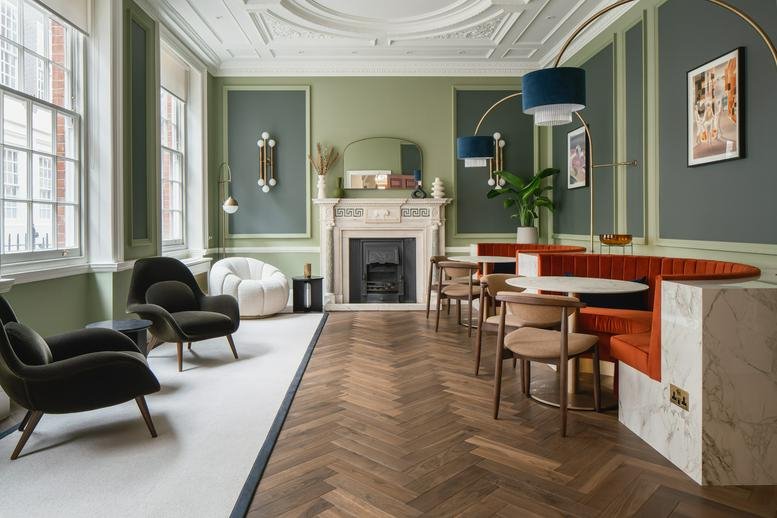 Elegant lounge area with velvet seating, a fireplace, and herringbone wood floors.