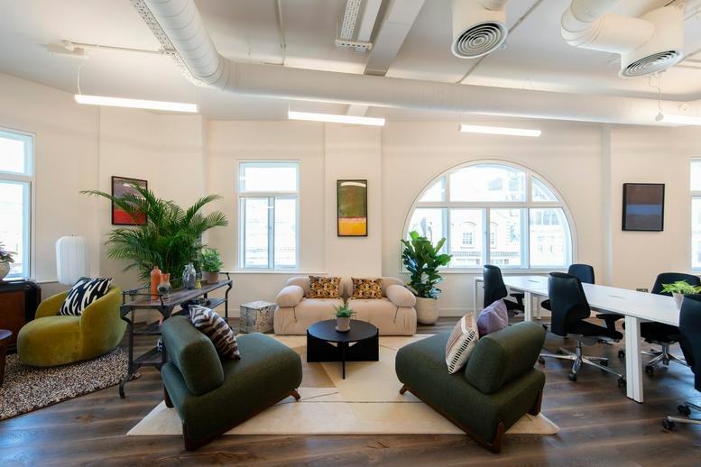 Spacious communal lounge at 88 Kingsway with green velvet chairs, a beige sofa, and potted plants.