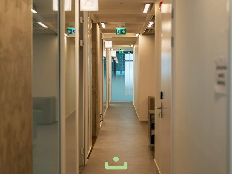 Modern bright corridor with glass-walled private offices and wooden ceiling accents.