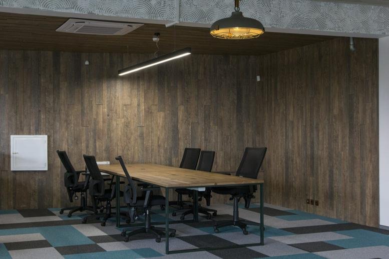 Spacious meeting room at 9 Anna Ahmatova Street featuring a long wooden table and wood-paneled walls.