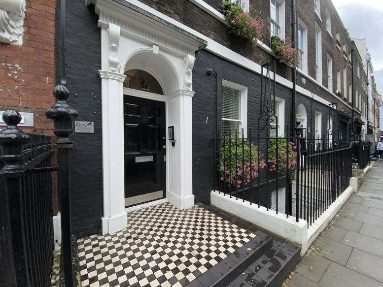 The classic brick and black facade of 9 Percy Street, London, Camden with white arched entrance.