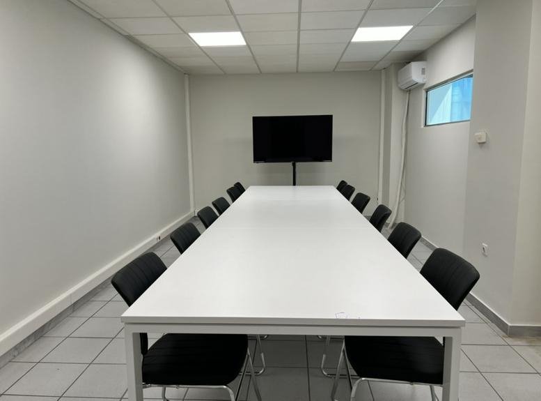 Meeting room at 90 October 26th, Porto Center featuring a long white table and wall-mounted screen.