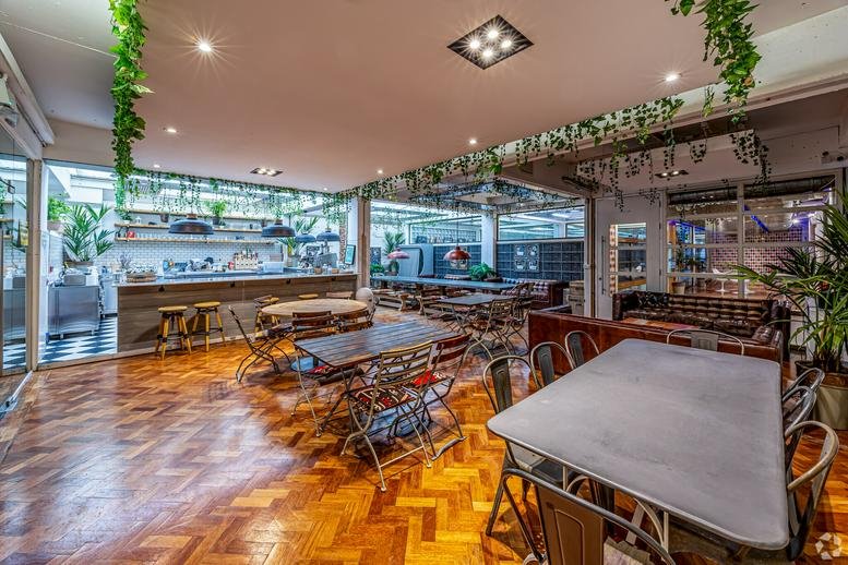 Spacious breakout area with parquet floors, hanging plants, and various casual seating arrangements.