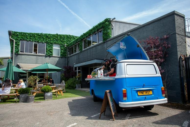 The 91 Peterborough Road building facade featuring green ivy-covered walls and a blue cafe van.