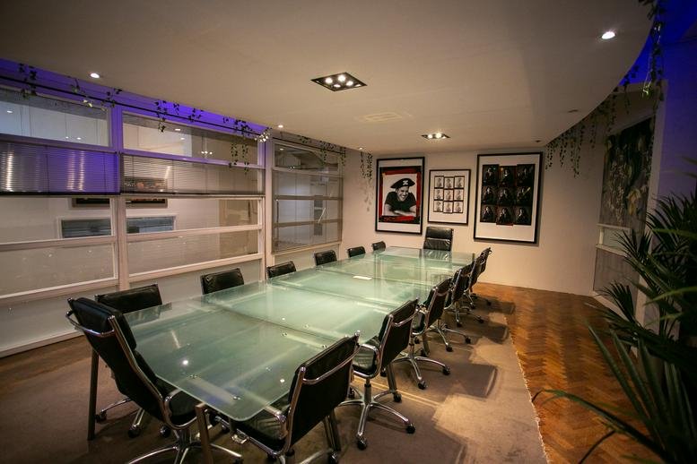 Formal conference room with a long glass table and framed art on the walls.