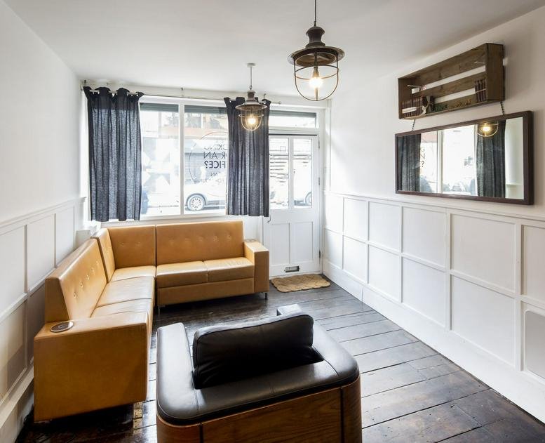 Bright, industrial-style lounge area at 92 Hoxton Street, Hackney featuring tan leather seating and wood paneling.