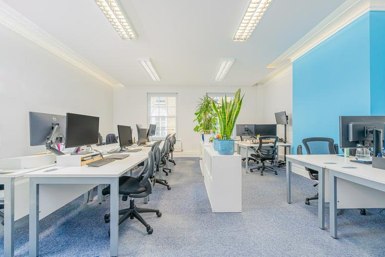 Spacious open-plan workspace at 96 High Street, Guildford, Surrey with blue feature wall and potted plants.