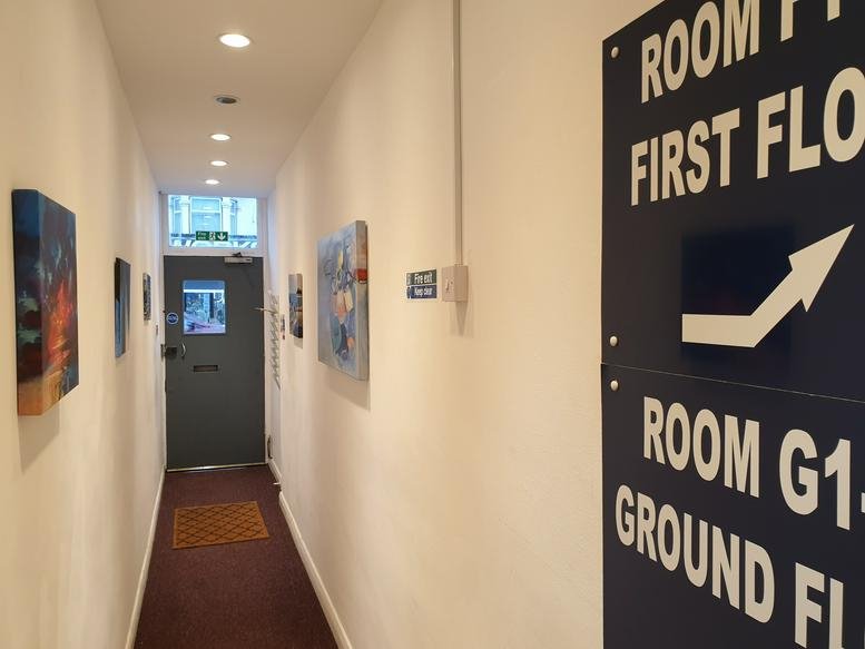 A narrow hallway at 96 Ilford Lane with artwork on the walls and a directory sign.