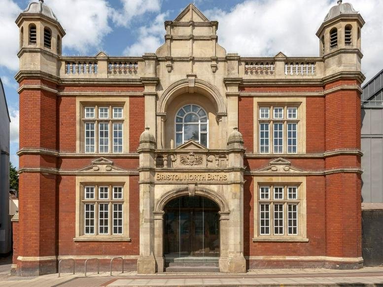 Historic red brick facade of Bristol North Baths with ornate stonework and arched entrance.