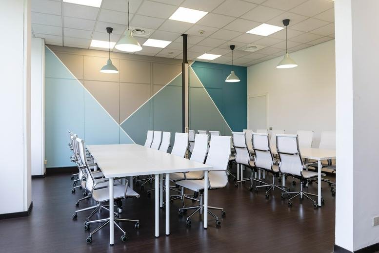 Meeting room at A&B Cinisello Balsamo, Viale Brianza 181 with teal geometric wall art and white chairs.