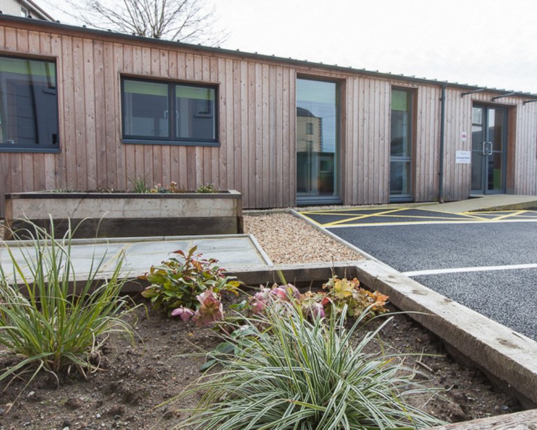 Modern timber-clad building exterior with large windows and integrated garden planters.
