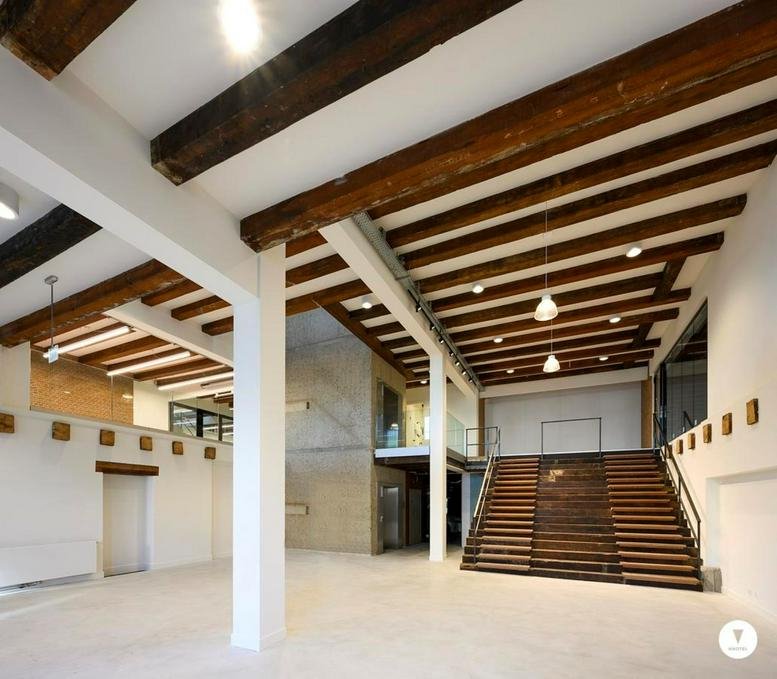 Spacious communal atrium at Achtergracht 4-22 featuring historic wood beams and a wide timber staircase.