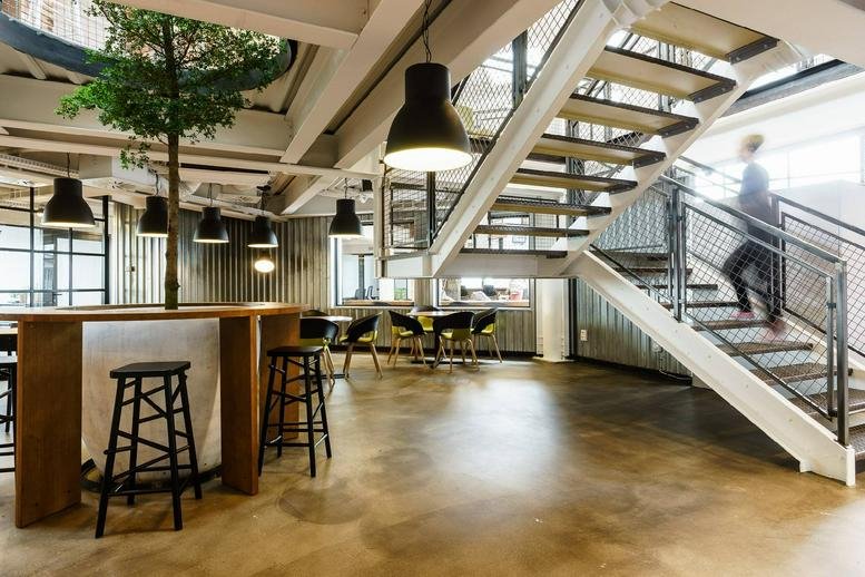 Spacious communal lounge at Adgar Park West with wooden accents and a feature tree.