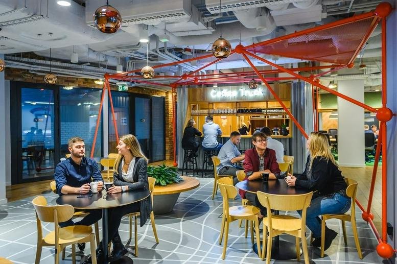 Colorful cafe and breakout area with a unique red geometric overhead structure at Adgar Plaza One.