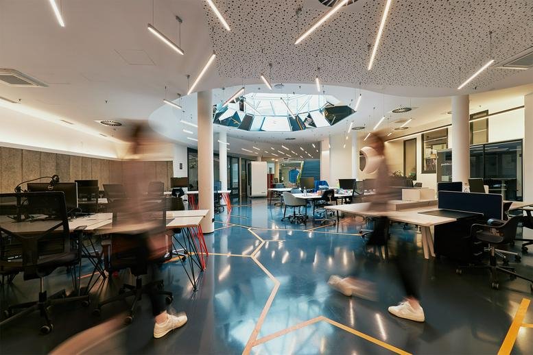 Bright, spacious open-plan lobby at Akazienstraße 3A with a central glass atrium.
